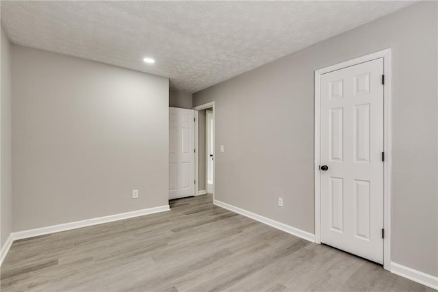 empty room featuring a textured ceiling and light wood-type flooring