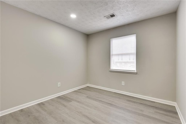 empty room featuring light wood-type flooring and a textured ceiling