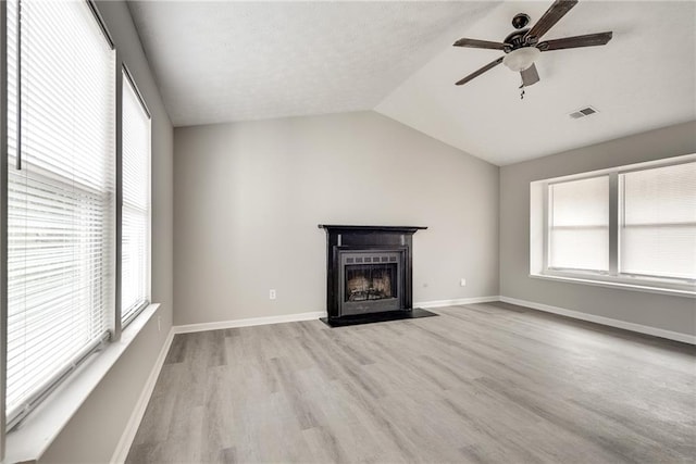 unfurnished living room with vaulted ceiling, light hardwood / wood-style flooring, plenty of natural light, and ceiling fan