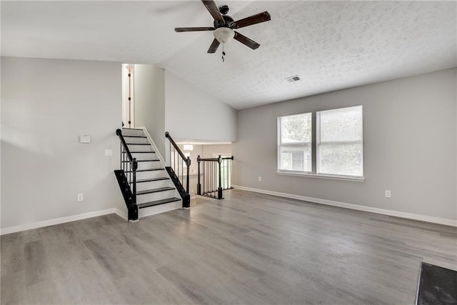 unfurnished living room with wood-type flooring, a textured ceiling, vaulted ceiling, and ceiling fan