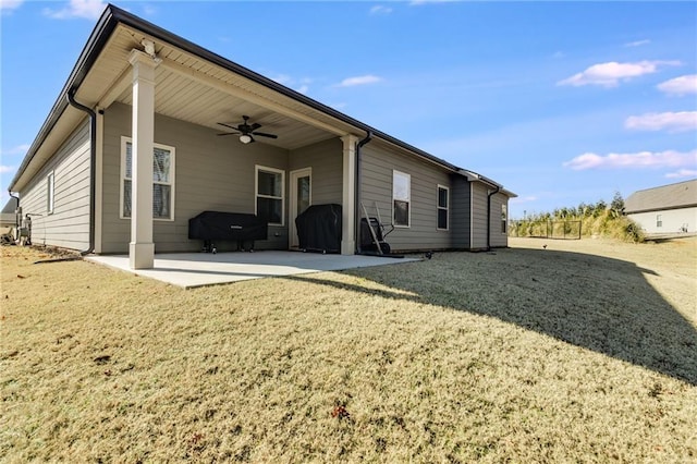 rear view of property with ceiling fan, a patio, and a lawn