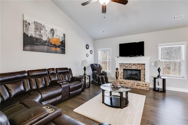 living room with a brick fireplace, ceiling fan, vaulted ceiling, and dark wood-type flooring