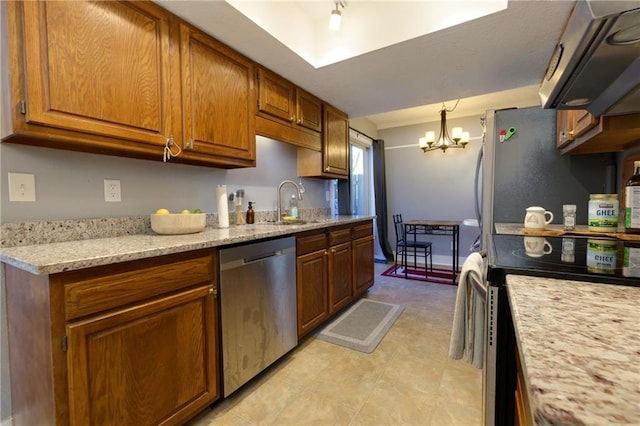 kitchen featuring light stone counters, brown cabinets, a notable chandelier, stainless steel appliances, and a sink