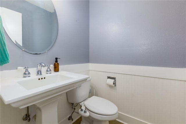 bathroom featuring toilet and a wainscoted wall