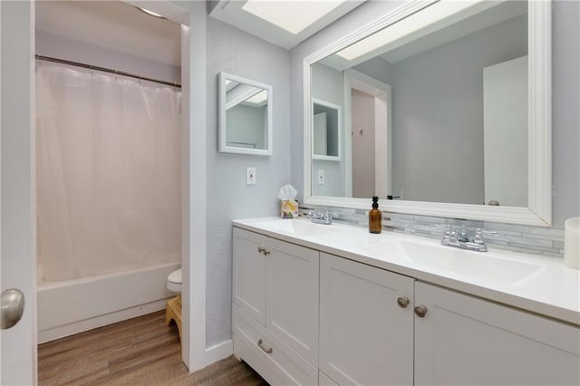 full bath with double vanity, tasteful backsplash, a sink, and wood finished floors