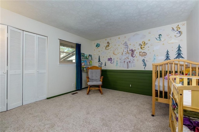 carpeted bedroom featuring a textured ceiling, a closet, visible vents, and wallpapered walls