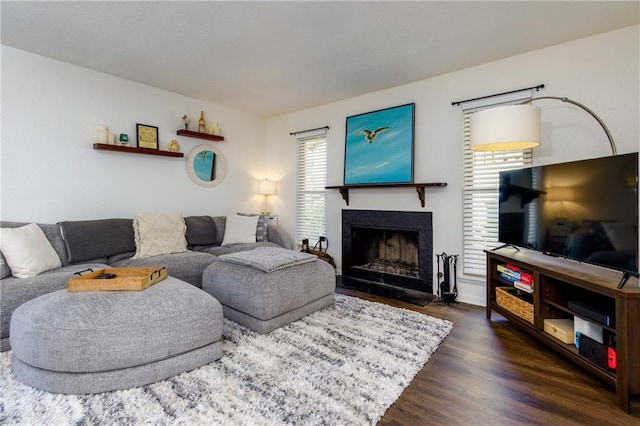 living room with dark wood-style floors and a fireplace with flush hearth