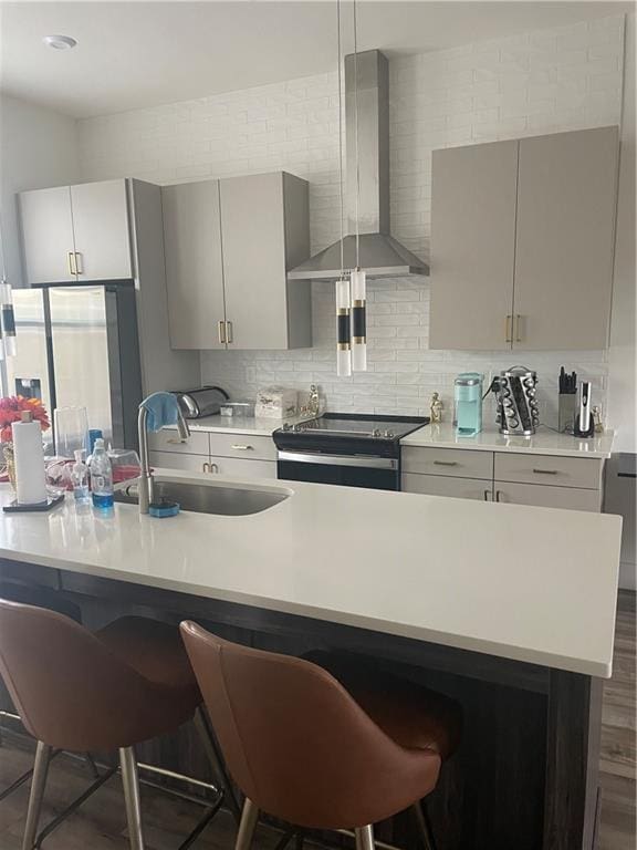 kitchen with light countertops, wall chimney range hood, and a breakfast bar area