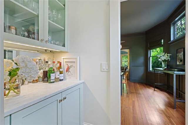 bar with baseboards, ornamental molding, and hardwood / wood-style flooring