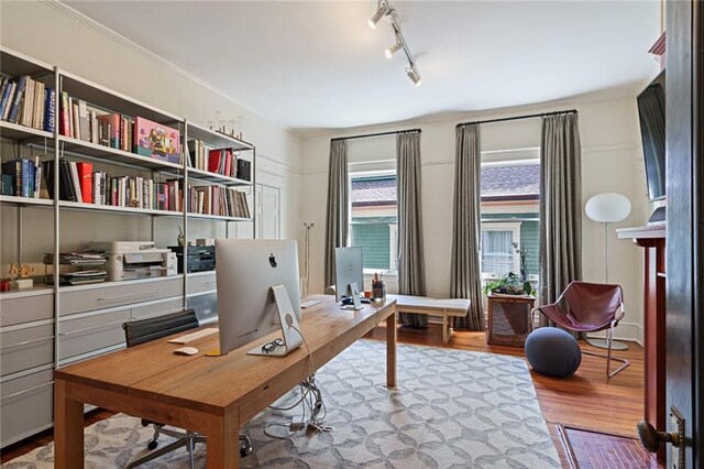 home office with rail lighting and wood finished floors