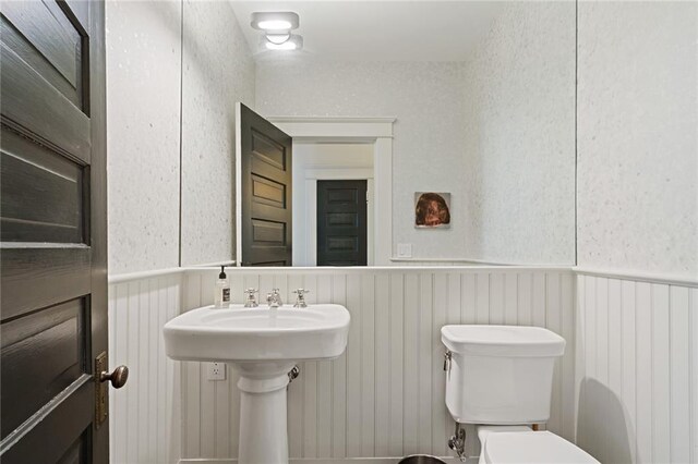 bathroom with toilet and a wainscoted wall