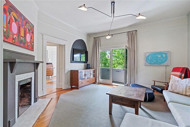 living area featuring ornamental molding, a fireplace, and wood finished floors