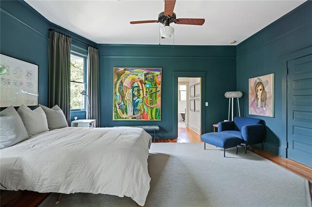 bedroom with baseboards, a ceiling fan, connected bathroom, and wood finished floors