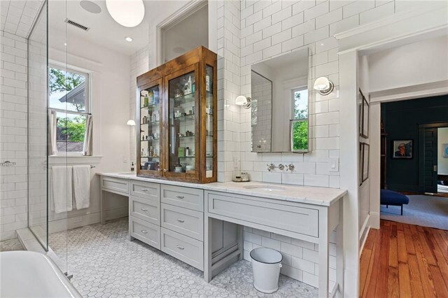full bathroom featuring a sink, double vanity, wood finished floors, a shower, and visible vents