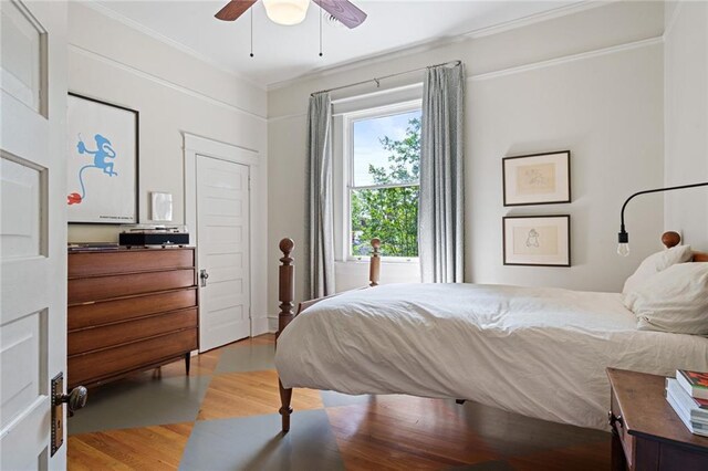 bedroom featuring ornamental molding, a ceiling fan, and light wood-type flooring