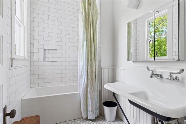 bathroom featuring a sink, a wainscoted wall, tile patterned flooring, and shower / bath combination with curtain