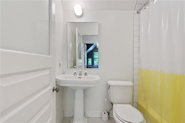 bathroom with toilet, baseboards, shower / bath combination with curtain, and tile patterned flooring