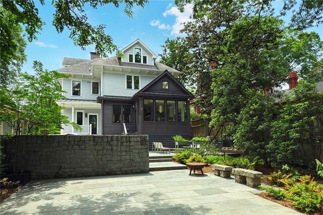 back of property with fence, a chimney, a sunroom, a shingled roof, and a patio area