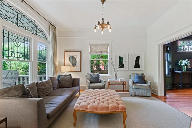 living room featuring an inviting chandelier, crown molding, and wood finished floors