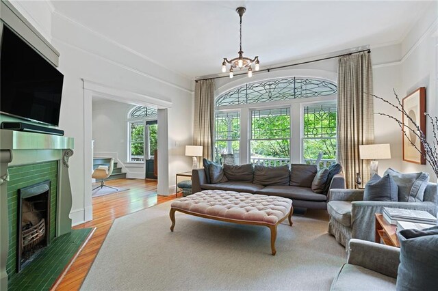 living room featuring a fireplace with flush hearth, an inviting chandelier, stairway, and light wood-style floors