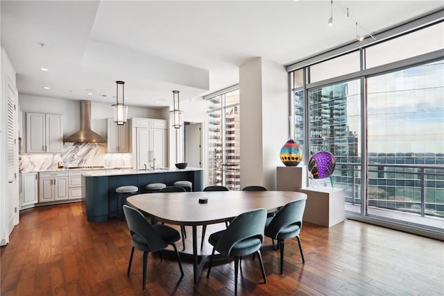 dining space with expansive windows, dark wood-type flooring, a city view, and recessed lighting