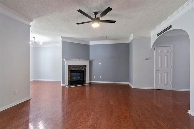 unfurnished living room featuring a premium fireplace, ornamental molding, ceiling fan, a textured ceiling, and dark hardwood / wood-style floors