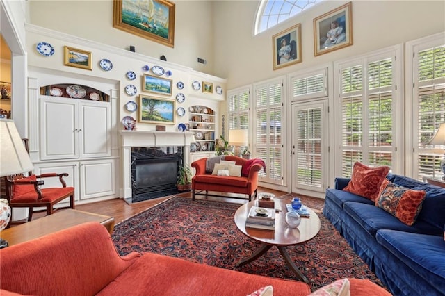 6259 Spalding Dr, Peachtree Corners, GA 30092 - living room with wood finished floors, a fireplace, built in features, a high ceiling, and ornamental molding