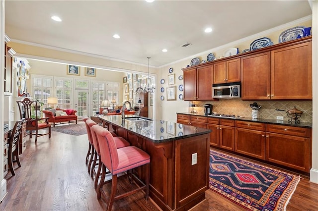 6259 Spalding Dr, Peachtree Corners, GA 30092 - kitchen featuring appliances with stainless steel finishes, crown molding, open floor plan, dark wood finished floors, and a kitchen bar
