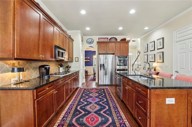 6259 Spalding Dr, Peachtree Corners, GA 30092 - kitchen featuring appliances with stainless steel finishes, ornamental molding, a sink, arched walkways, and a kitchen island with sink