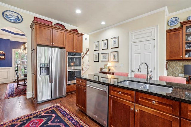 6259 Spalding Dr, Peachtree Corners, GA 30092 - kitchen featuring stainless steel appliances, a sink, ornamental molding, dark wood finished floors, and dark stone countertops