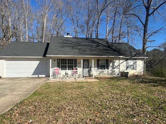 ranch-style house with driveway, a porch, an attached garage, and a front yard