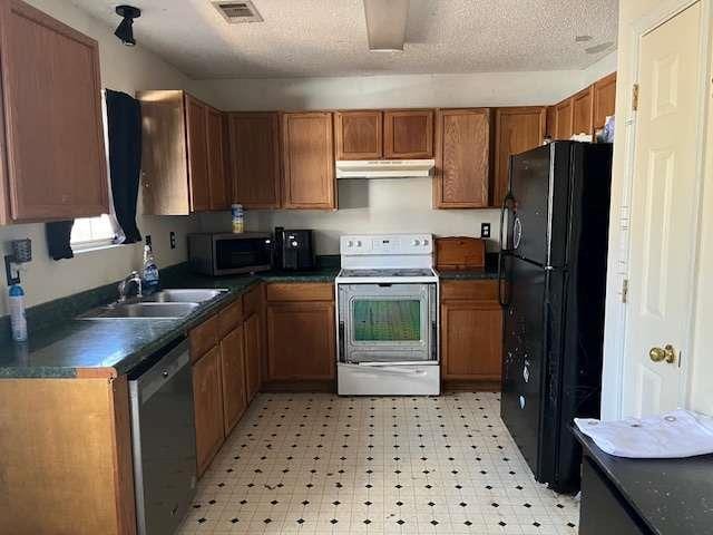 kitchen featuring dark countertops, visible vents, appliances with stainless steel finishes, a sink, and under cabinet range hood