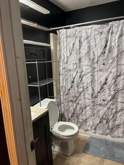 full bathroom featuring toilet, curtained shower, tile patterned floors, and vanity