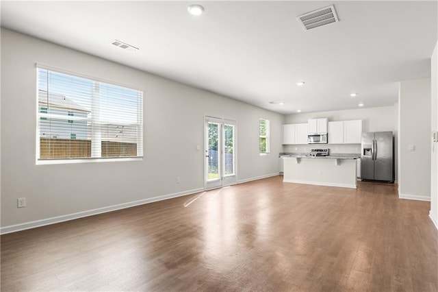 unfurnished living room featuring baseboards, wood finished floors, and visible vents