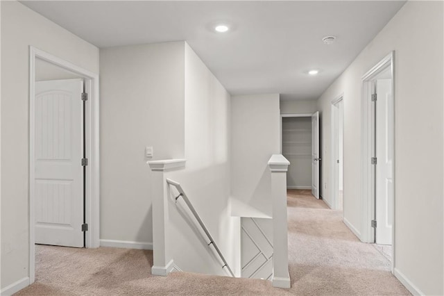 hallway featuring recessed lighting, baseboards, carpet floors, and an upstairs landing