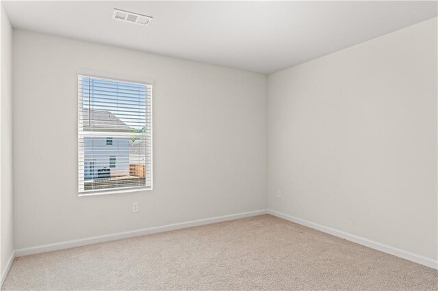 carpeted empty room featuring baseboards and visible vents