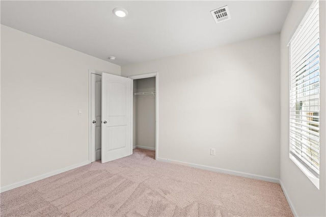 unfurnished bedroom with multiple windows, visible vents, a closet, and light carpet