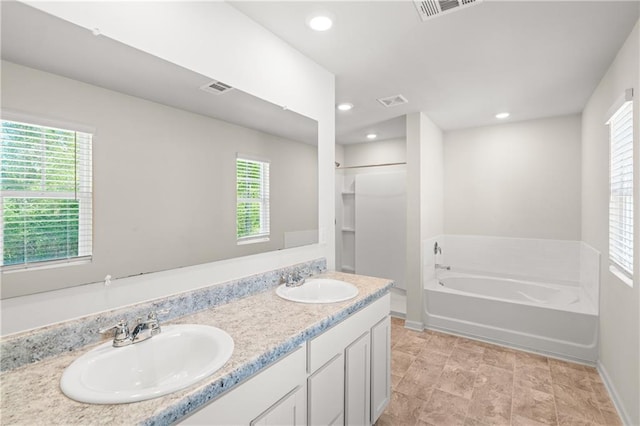 bathroom featuring visible vents, a garden tub, and a sink