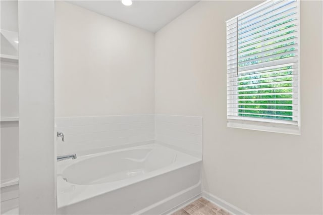 bathroom with a bath and baseboards