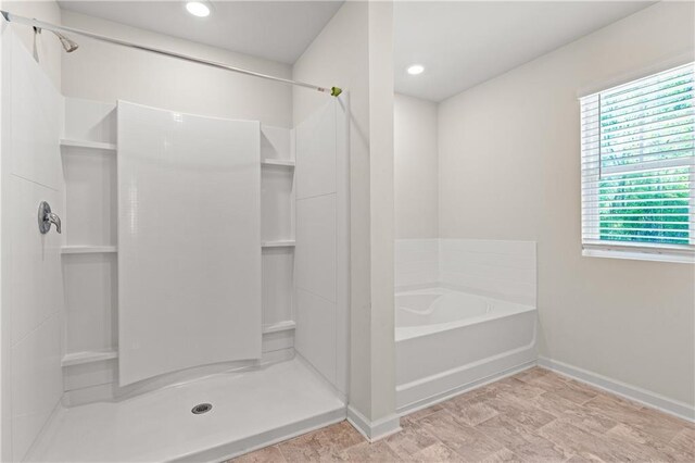 bathroom with a bath, baseboards, and a stall shower