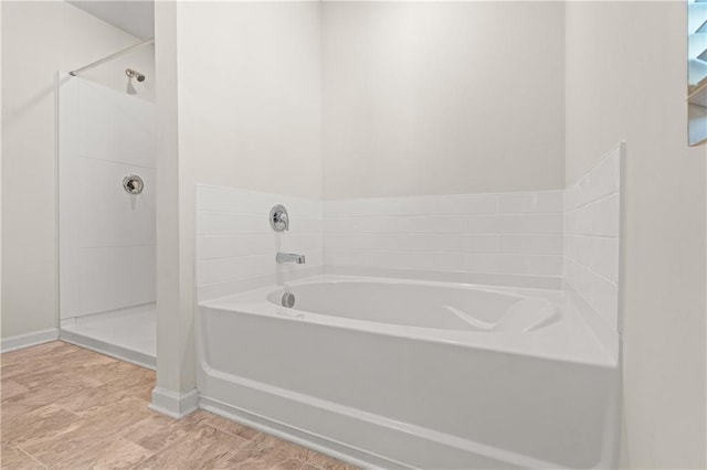bathroom featuring a bath, baseboards, and a walk in shower