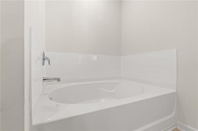 full bath with a garden tub and baseboards
