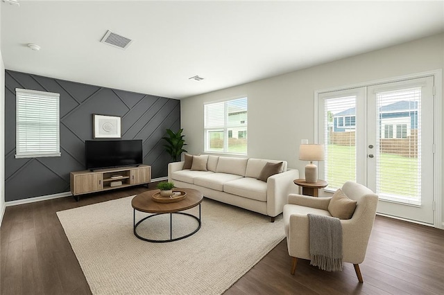 living room with visible vents, an accent wall, and dark wood-type flooring