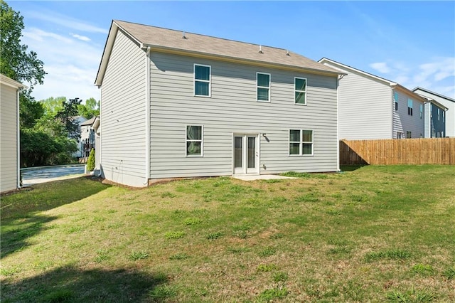 rear view of property featuring a lawn and fence