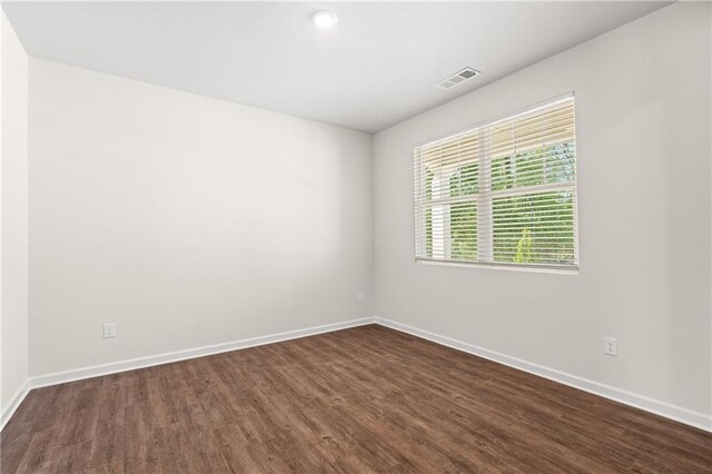 spare room with baseboards, visible vents, and dark wood-style floors