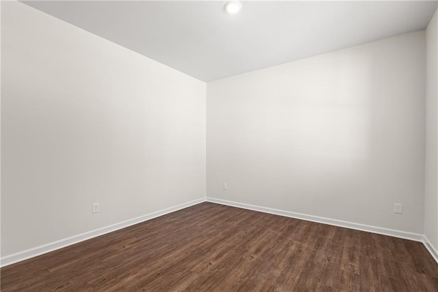 empty room featuring baseboards and dark wood-style floors