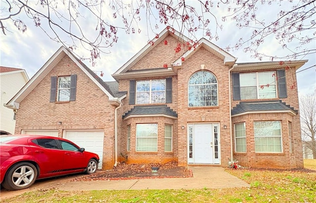 view of front of property featuring a garage, roof with shingles, and brick siding