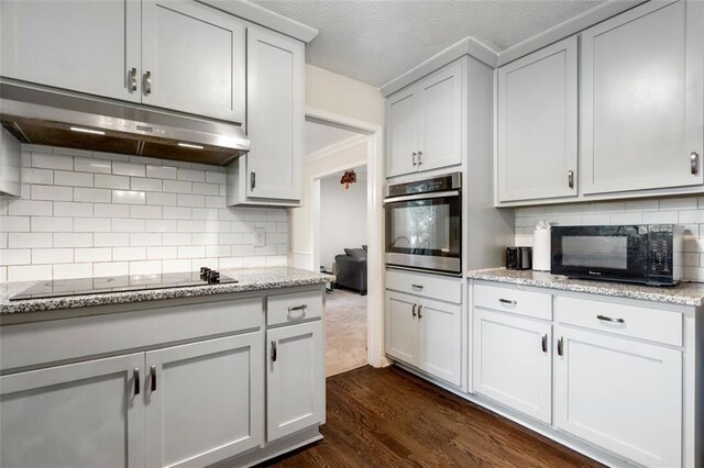 kitchen with light stone countertops, tasteful backsplash, dark hardwood / wood-style flooring, and black appliances