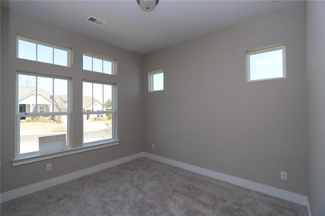 empty room featuring visible vents, carpet, and baseboards