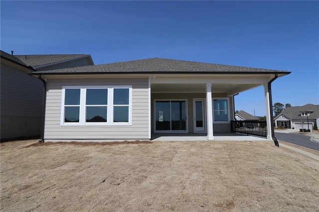 rear view of property featuring a shingled roof and a patio